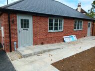 A new bungalow with a ramp and grey door