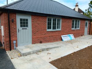 A new bungalow with a ramp and grey door