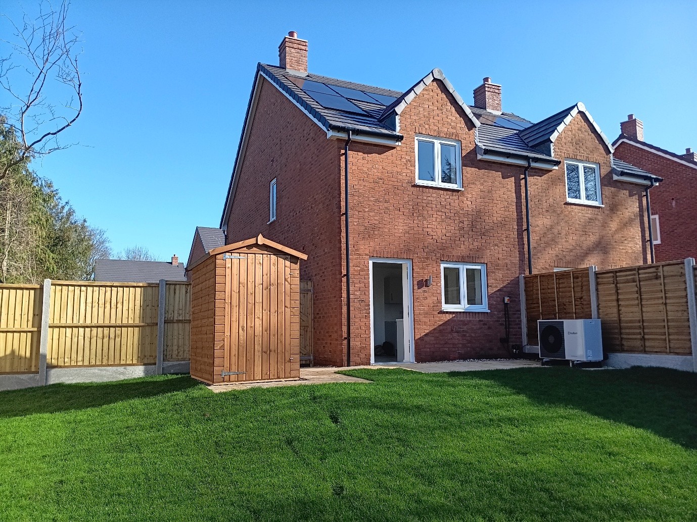 A new build with a green grass and a shed