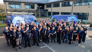 Two Rivers Housing Team in matching blue uniforms raising their arms in a cheer.