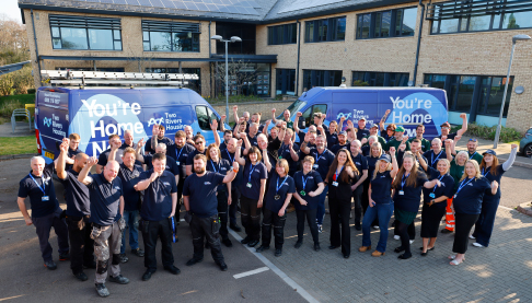 Two Rivers Housing Team in matching blue uniforms raising their arms in a cheer.